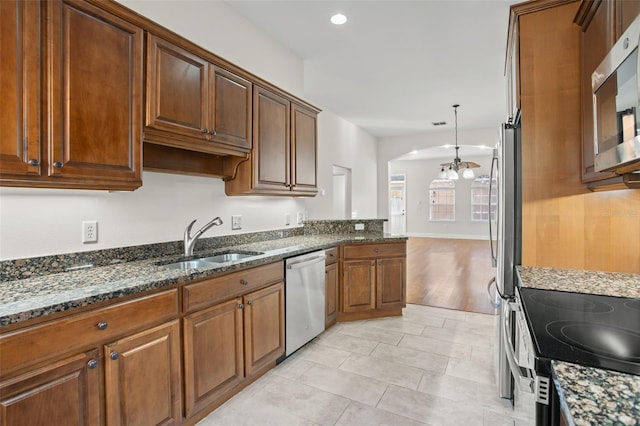 kitchen featuring dark stone counters, an inviting chandelier, sink, appliances with stainless steel finishes, and decorative light fixtures