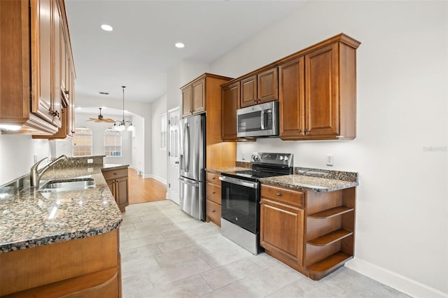 kitchen featuring ceiling fan, sink, dark stone counters, pendant lighting, and appliances with stainless steel finishes