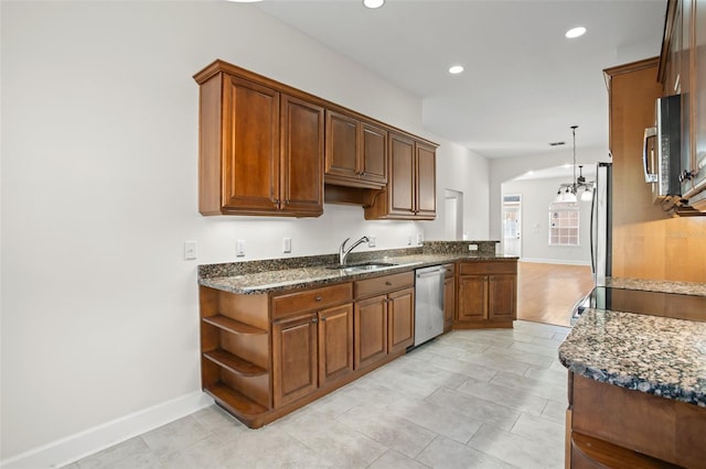 kitchen with dark stone counters, sink, hanging light fixtures, kitchen peninsula, and stainless steel appliances