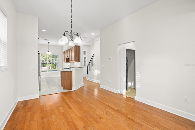 kitchen with sink, stainless steel fridge, a chandelier, light hardwood / wood-style floors, and decorative light fixtures