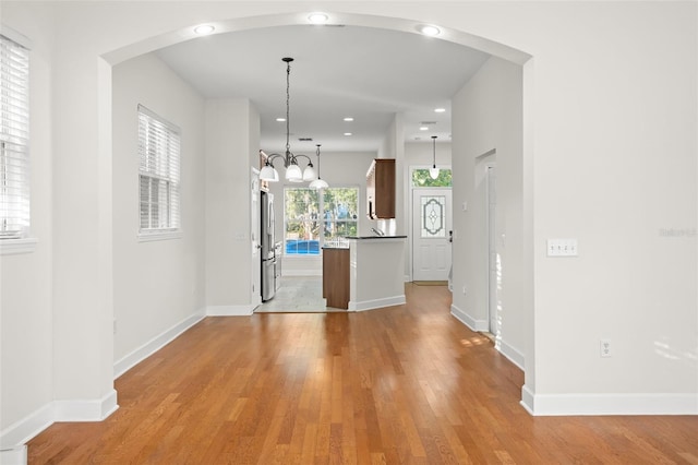 unfurnished dining area featuring an inviting chandelier and light wood-type flooring