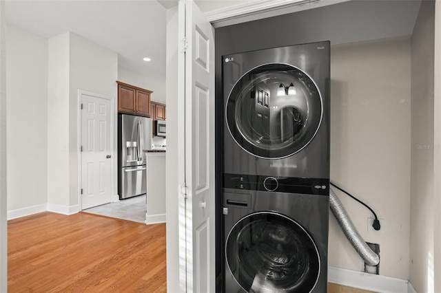 laundry room featuring stacked washer / drying machine and light hardwood / wood-style flooring