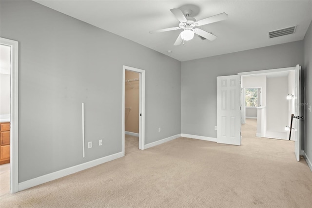 unfurnished bedroom with light carpet, a closet, a spacious closet, and ceiling fan