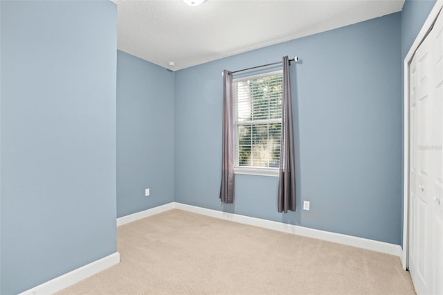 unfurnished bedroom with light colored carpet and a closet