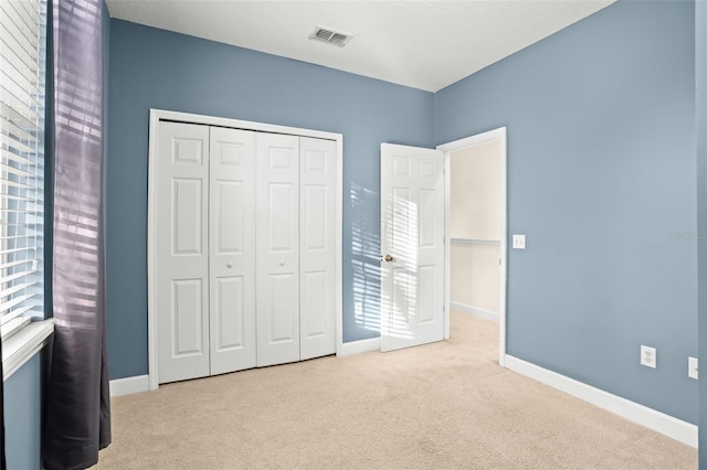 unfurnished bedroom with light carpet, multiple windows, and a closet