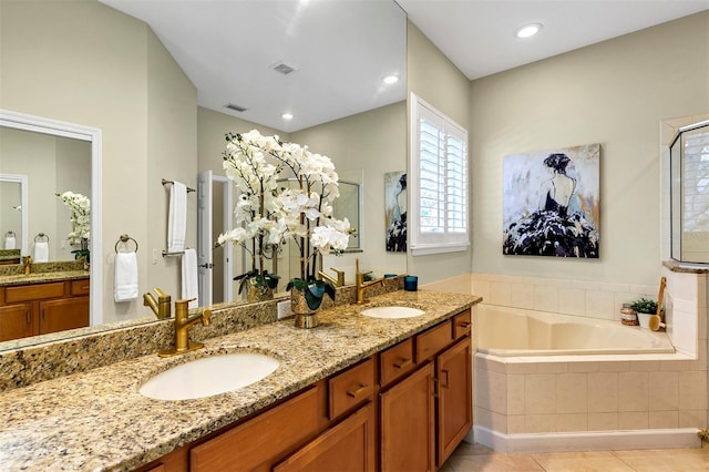 bathroom featuring tile patterned floors, vanity, and a relaxing tiled tub