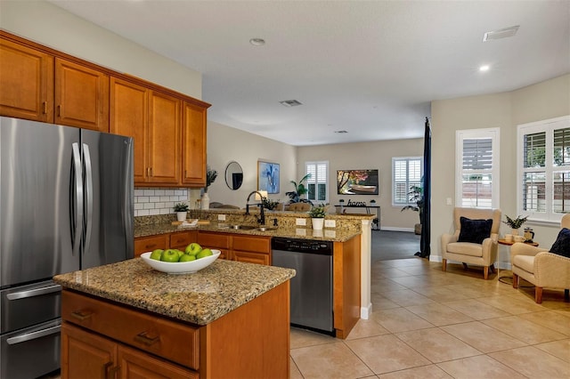 kitchen featuring kitchen peninsula, appliances with stainless steel finishes, a kitchen island, and sink