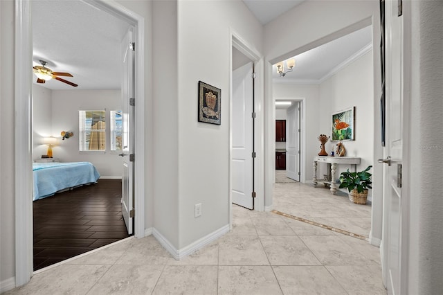 hall with light tile patterned flooring, ornamental molding, and a textured ceiling