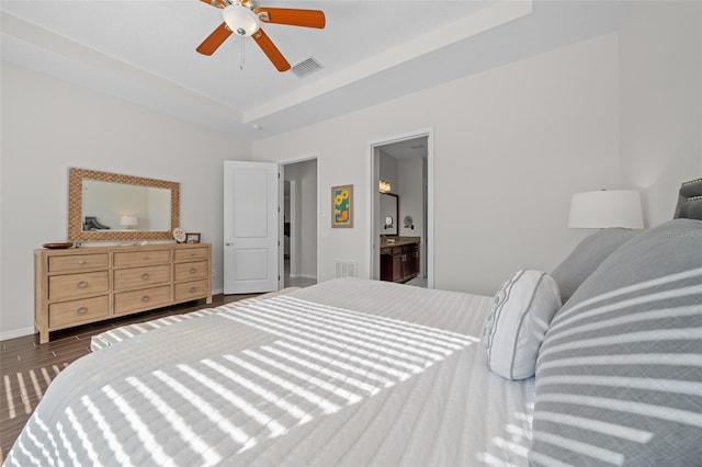 bedroom featuring a tray ceiling, ensuite bath, and ceiling fan