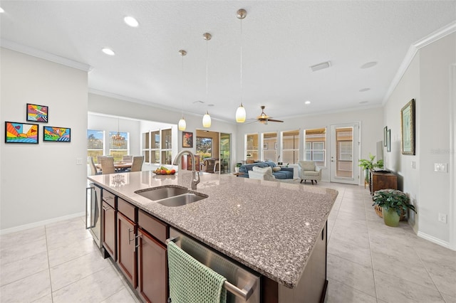 kitchen with ceiling fan, sink, crown molding, pendant lighting, and a kitchen island with sink