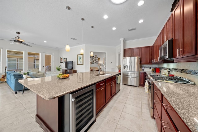 kitchen featuring wine cooler, an island with sink, decorative light fixtures, appliances with stainless steel finishes, and ornamental molding