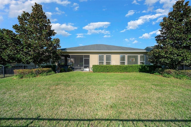 rear view of house featuring a yard and a sunroom