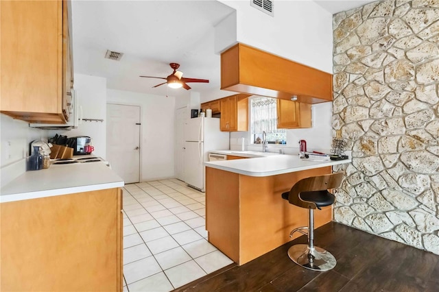 kitchen with sink, a kitchen breakfast bar, kitchen peninsula, white fridge, and ceiling fan