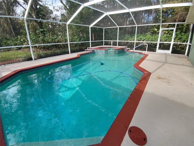 view of pool with an in ground hot tub, glass enclosure, and a patio area