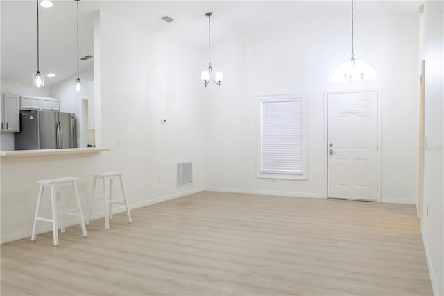 interior space featuring stainless steel refrigerator, decorative light fixtures, a chandelier, and white cabinetry