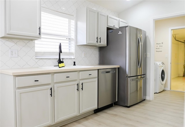 kitchen featuring white cabinets, stainless steel appliances, light wood-type flooring, and independent washer and dryer