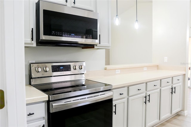 kitchen featuring stainless steel appliances, white cabinets, and pendant lighting