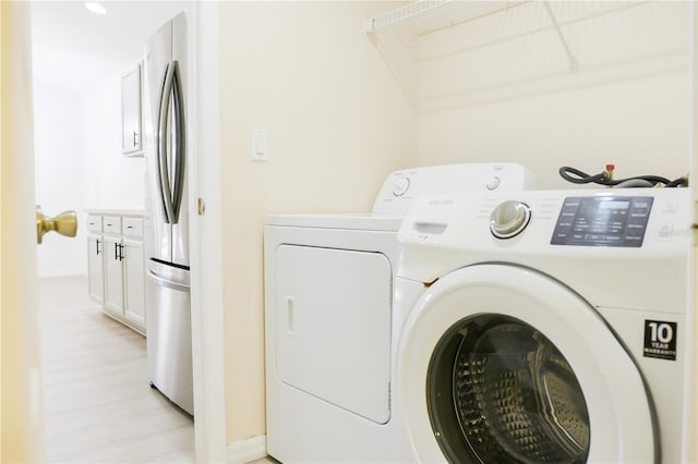 laundry room featuring washer and clothes dryer and light hardwood / wood-style floors