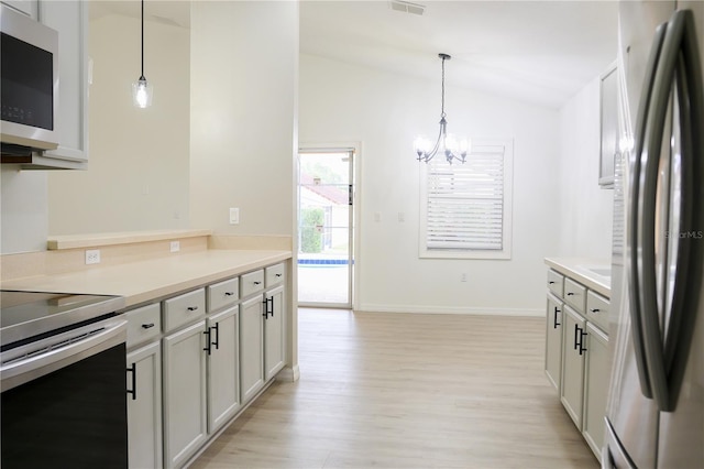 kitchen with decorative light fixtures, an inviting chandelier, lofted ceiling, light hardwood / wood-style floors, and appliances with stainless steel finishes