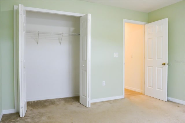 unfurnished bedroom with a closet and light colored carpet