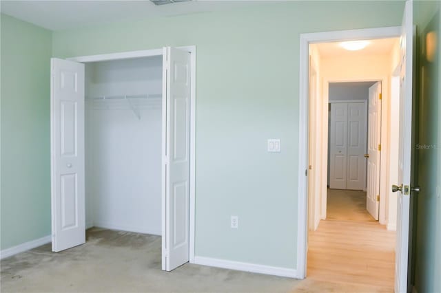 unfurnished bedroom with light colored carpet and a closet