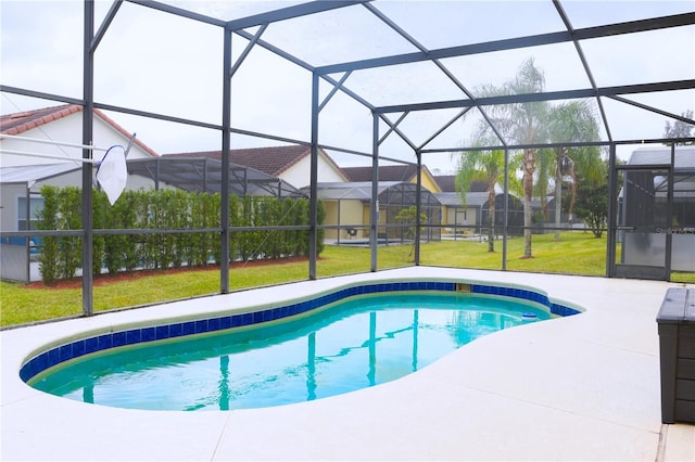 view of pool featuring a lawn, glass enclosure, and a patio