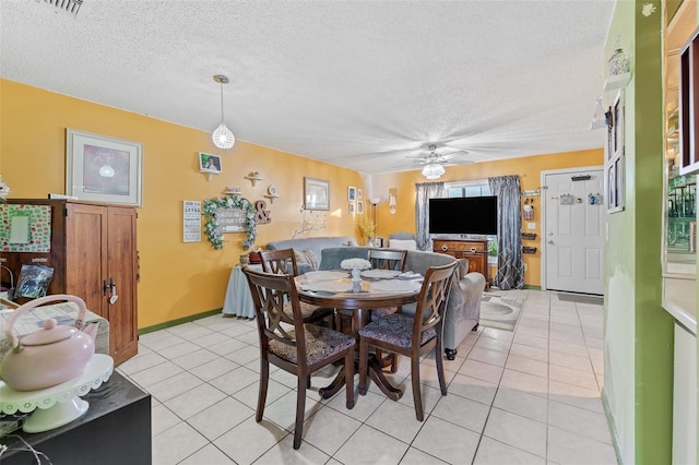 dining area featuring light tile patterned flooring, ceiling fan, a textured ceiling, and baseboards