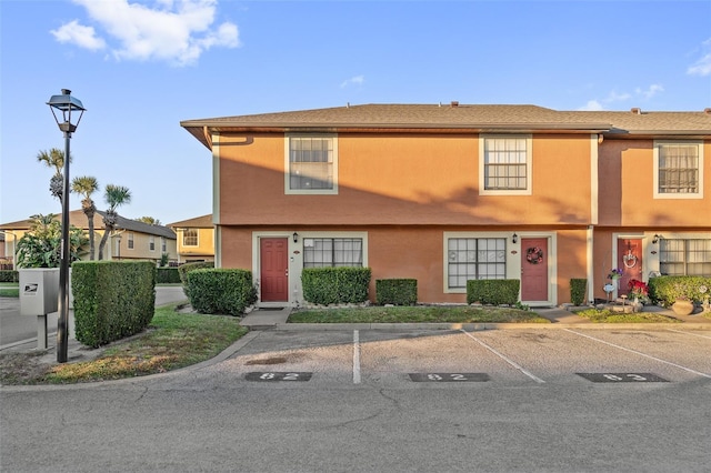 view of property featuring uncovered parking and stucco siding