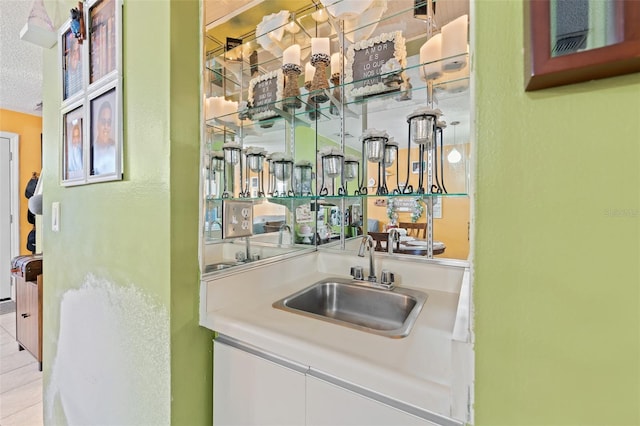 bar with indoor wet bar, light tile patterned flooring, a sink, and a textured ceiling