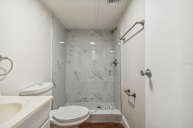 bathroom featuring tiled shower, vanity, and toilet