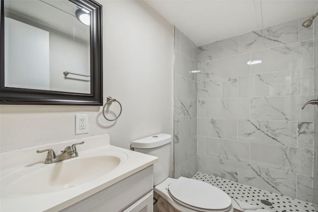 bathroom with a tile shower, vanity, and toilet