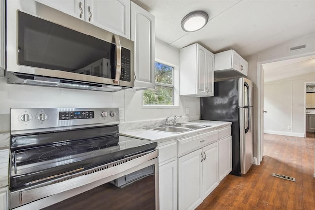 kitchen with white cabinetry, sink, appliances with stainless steel finishes, and vaulted ceiling