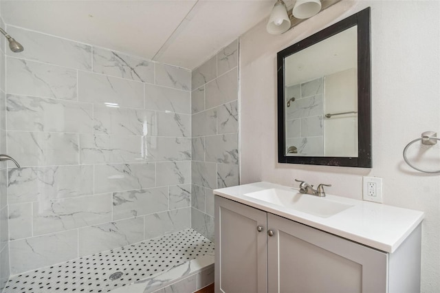 bathroom with a tile shower and vanity