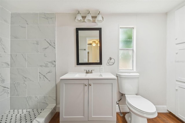 bathroom featuring tiled shower, toilet, vanity, and hardwood / wood-style flooring