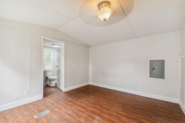 interior space with dark hardwood / wood-style flooring, connected bathroom, electric panel, and lofted ceiling