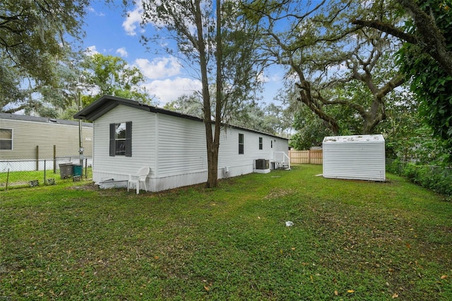 4611 Gall Blvd, Zephyrhills, FL 33542 - exterior space with a lawn, an outbuilding, a shed, central AC unit, and a fenced backyard