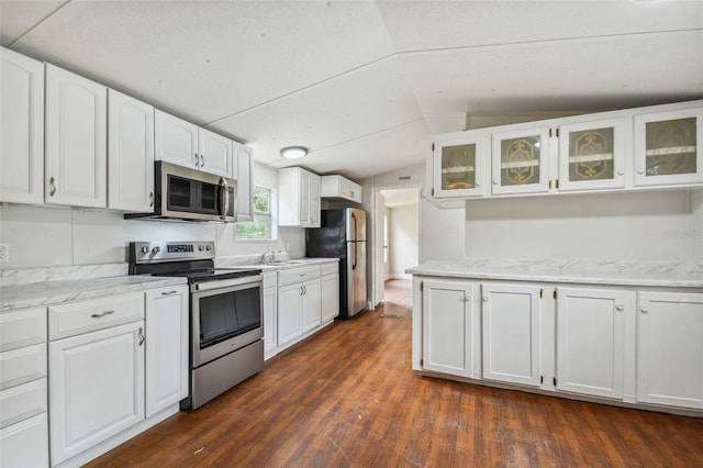 4611 Gall Blvd, Zephyrhills, FL 33542 - kitchen with lofted ceiling, glass insert cabinets, dark wood finished floors, white cabinetry, and stainless steel appliances