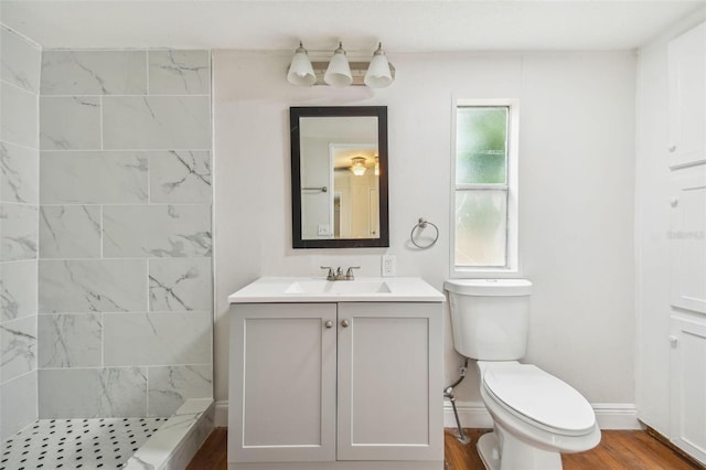 4611 Gall Blvd, Zephyrhills, FL 33542 - bathroom with toilet, baseboards, a tile shower, vanity, and wood finished floors