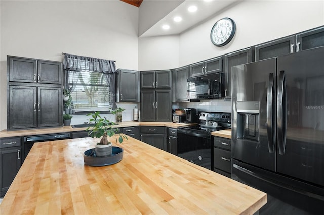 kitchen featuring decorative backsplash, a high ceiling, butcher block countertops, and black appliances