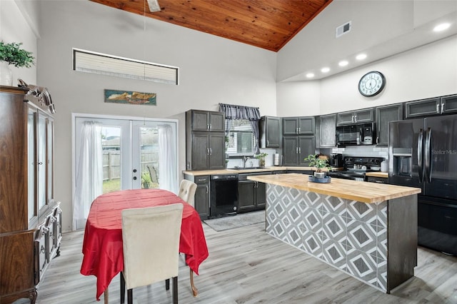 kitchen featuring french doors, high vaulted ceiling, wooden counters, a kitchen island, and black appliances