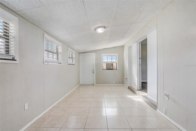 interior space featuring a paneled ceiling, vaulted ceiling, cooling unit, and light tile patterned flooring