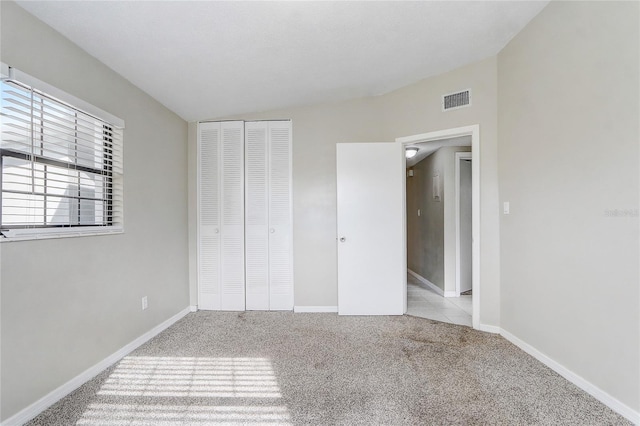 unfurnished bedroom featuring light colored carpet and a closet