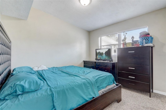 bedroom with light colored carpet and a textured ceiling