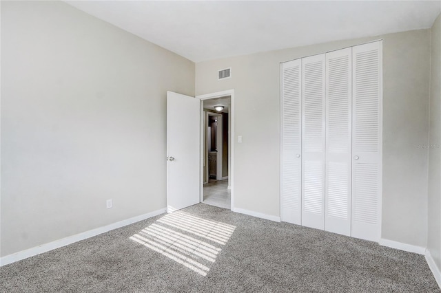 unfurnished bedroom featuring light carpet, a closet, and vaulted ceiling