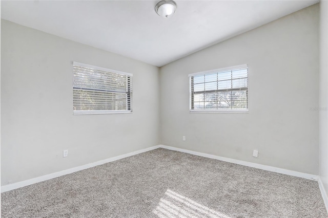 carpeted spare room with lofted ceiling