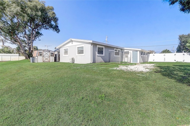 back of property featuring a yard and a storage unit