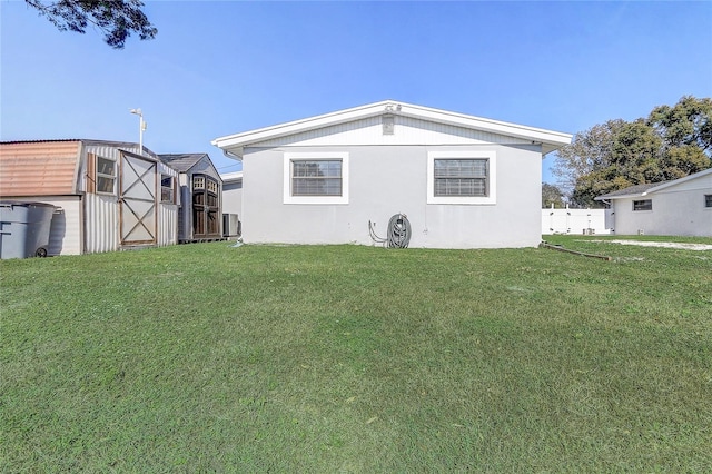 back of house with a yard and a storage shed