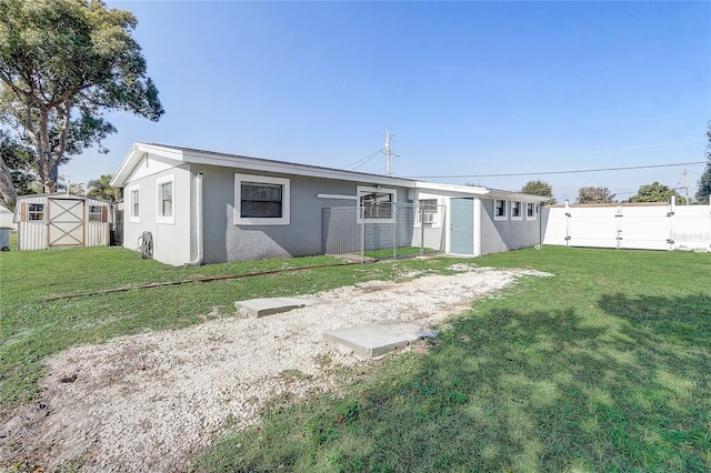 back of house with a yard and a storage unit