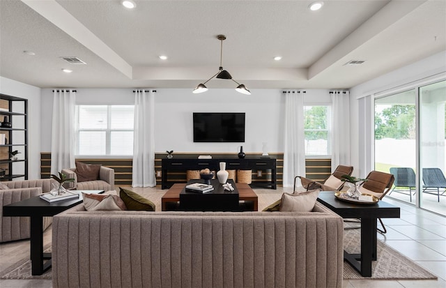 living room featuring light tile patterned floors, a textured ceiling, and a tray ceiling