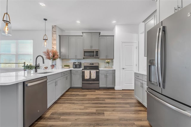 kitchen featuring gray cabinets, sink, pendant lighting, and appliances with stainless steel finishes